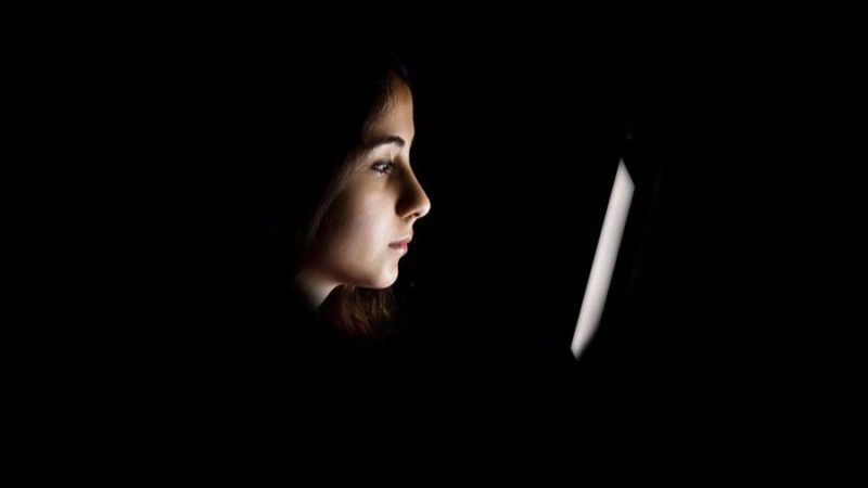 Mujer mirando pantalla a oscuras