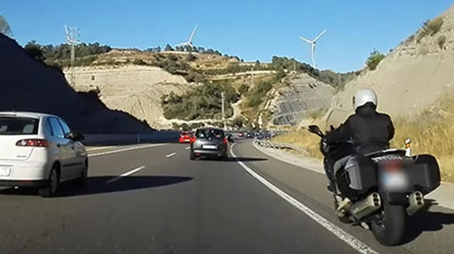 En moto por el arcén, con guantes en carretera y conectados al móvil