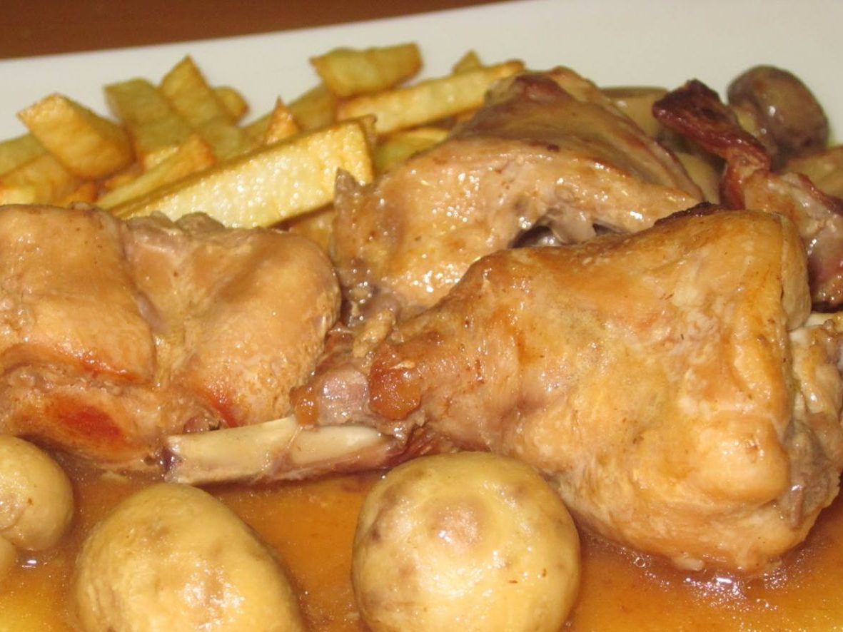 Un plato de conejo asado con salsa de champiñones y piñones