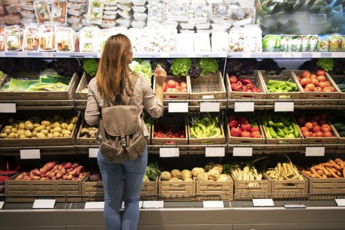 good looking woman standing front vegetable shelves choosing what buy Merca2.es