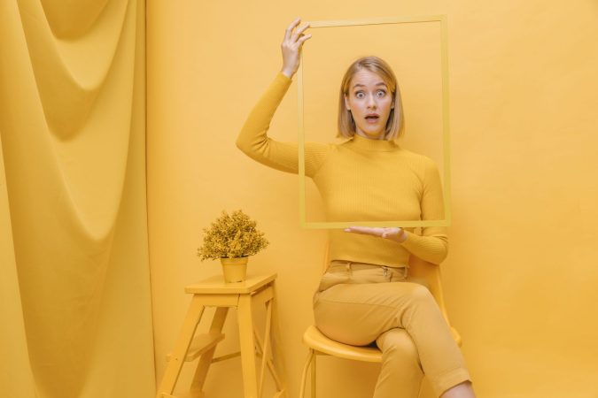 woman holding frame around face yellow scene Merca2.es