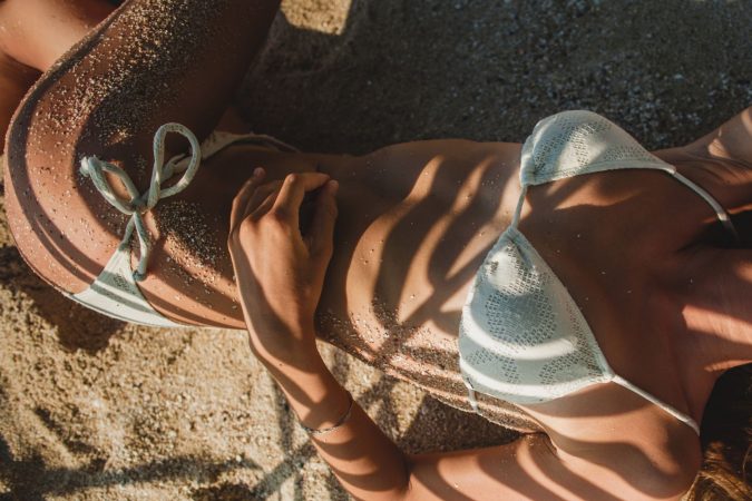 young woman laying sand beach palm tree leaf Merca2.es