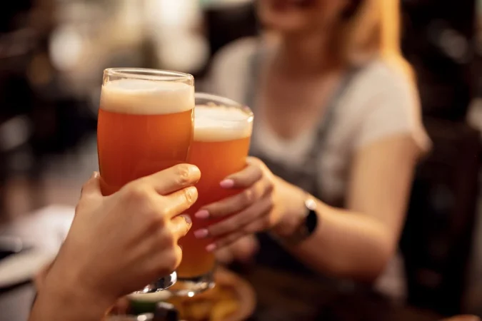 close up unrecognizable couple toasting with lager beer bar Merca2.es