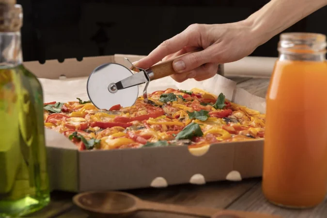 hand cutting pizza with tool close up Merca2.es