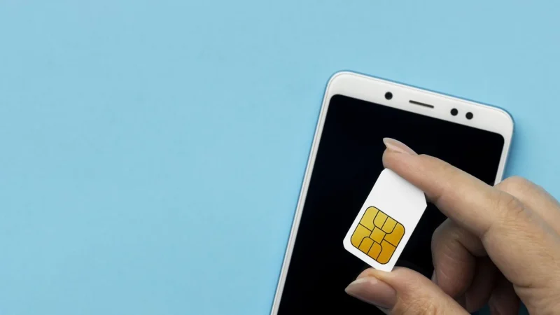 top view hand holding sim card with smartphone copy space Merca2.es