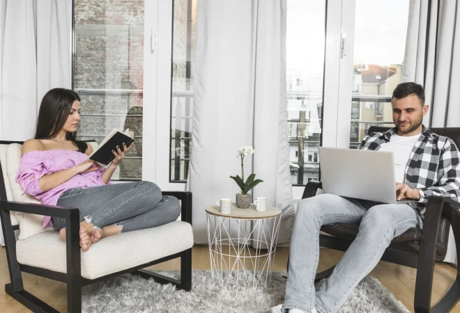 young woman busy reading book her boyfriend using laptop home Merca2.es