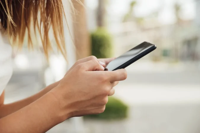 young woman holding black smartphone Merca2.es