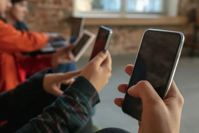 group happy young young people sitting sofa together sharing news photos videos from smartphones reading articles playing games having fun social media modern technologies Merca2.es