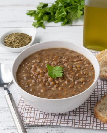 brown lentil soup bowl with bread slices seasoning wooden table Merca2.es