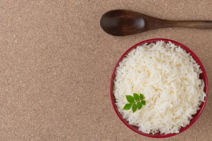 arroz cocido en una taza roja colocada en el piso de madera contrachapada Merca2.es