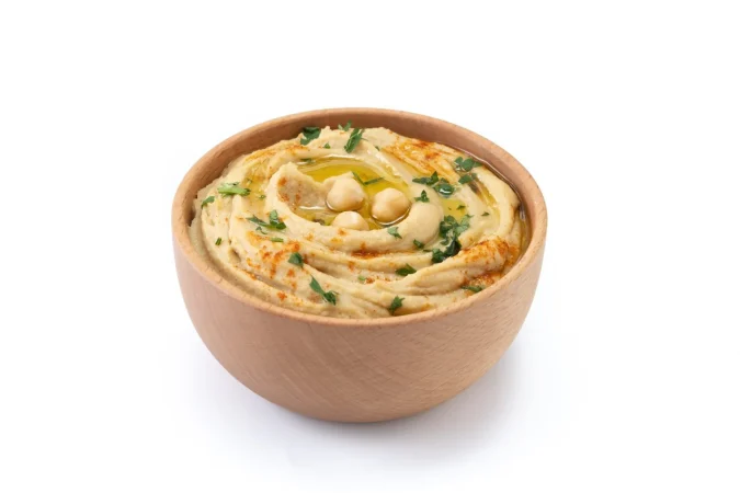 hummus de garbanzos en un cuenco de madera adornado con pimenton de perejil y aceite de oliva aislado sobre fondo blanco cerrar Merca2.es