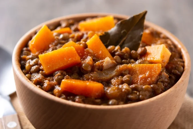 ragout de estofado de lentejas con calabaza y zanahoria en un tazon sobre mesa de madera Merca2.es