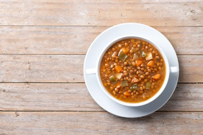 sopa de lentejas con verduras en un cuenco en una mesa de madera 1 Merca2.es