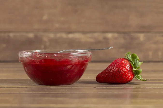 Cómo hacer mermelada de fresa casera como la de las abuelas 3 Merca2.es superficie de madera con fresa y mermelada de fresa Merca2.es