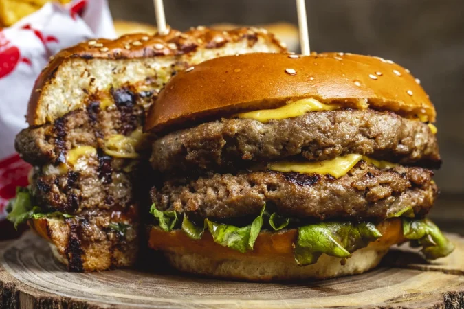 vista lateral doble hamburguesa con queso con empanadas de carne la parrilla queso y hojas de lechuga entre bollos Merca2.es