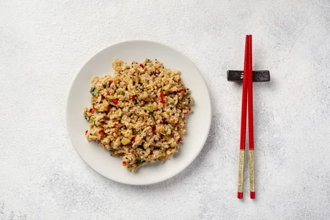 vista superior de arroz con verduras en plato y palillos Merca2.es