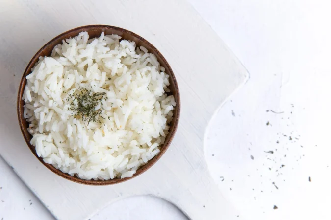 vista superior de la comida sabrosa de arroz cocido dentro de una olla marron con pimienta en la superficie blanca Merca2.es