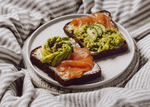 alto angulo de sandwiches de desayuno en la cama con salmon y aguacate Merca2.es
