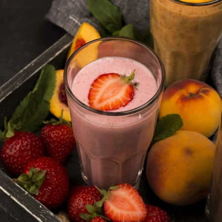 alto angulo de vaso de batido con fresa y melocotones Merca2.es