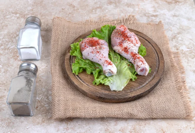 carne de muslos de pollo sin cocer con verduras sobre una tabla de madera Merca2.es