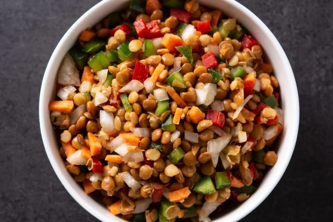Ensalada de lentejas: sana, nutritiva y completamente a tu gusto 6 Merca2.es ensalada de lentejas con peppersonion y zanahoria en un bol sobre fondo de pizarra negra Merca2.es