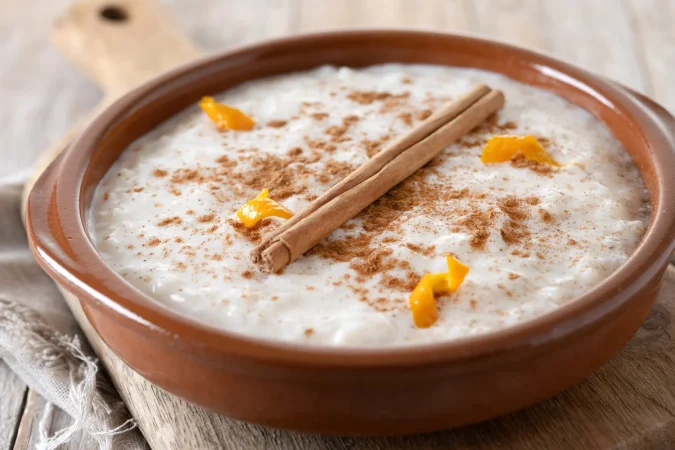arroz con leche arroz con leche con canela en cuenco de arcilla sobre mesa de madera Merca2.es