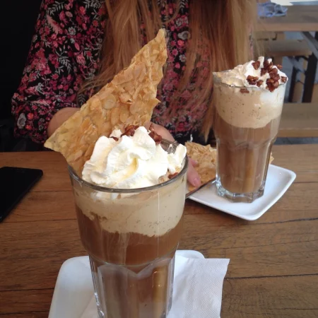 vista de angulo alto de cafe helado en la mesa contra la mujer Merca2.es