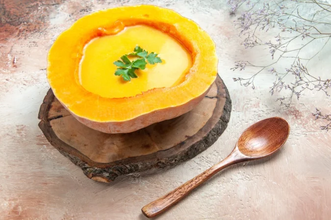 vista lateral de cerca una sopa sopa de calabaza en el tablero junto las ramas de los arboles de cuchara Merca2.es