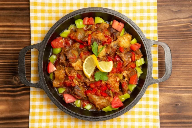 vista superior de comida vegetal cocida con carne y pimientos en rodajas dentro de la sarten en el escritorio marron Merca2.es