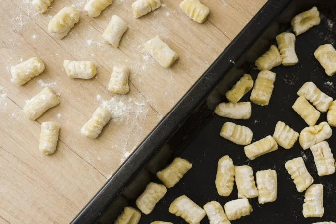 primer plano de pasta de noquis de papa casera sin cocer en bandeja de hornear y escritorio Merca2.es