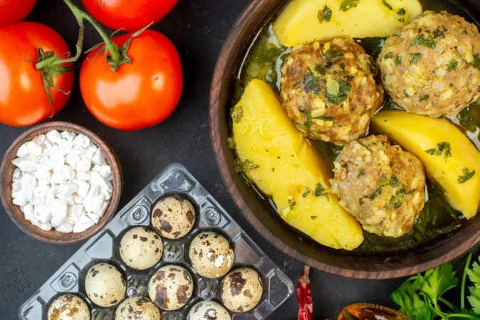 vista de cerca de sabrosos huevos de comida de albondigas tomates de sal verde con tallos sobre fondo negro Merca2.es