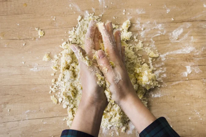 primer plano de la mano de una mujer amasando la masa para preparar noquis italianos en el escritorio de madera Merca2.es