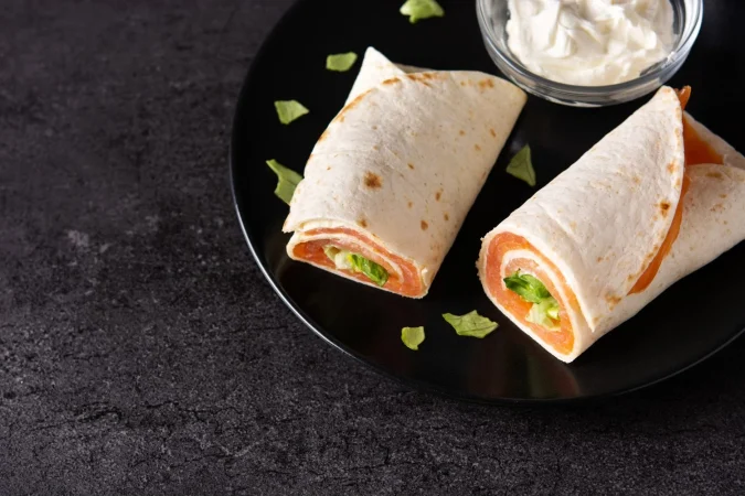 Burrito de pollo y verduras: la receta fácil que conquista medio mundo (y sus curiosidades más sorprendentes) 29 Merca2.es rollo de sandwich de envoltura de salmon con queso y verduras sobre fondo de piedra negra Merca2.es